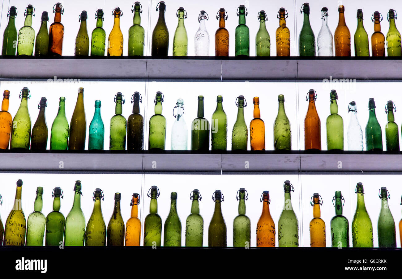 Molti diversi, vuoto, le bottiglie di birra, la maggior parte con il cappello di ceramica, stando in piedi in un ripiano illuminato, Foto Stock