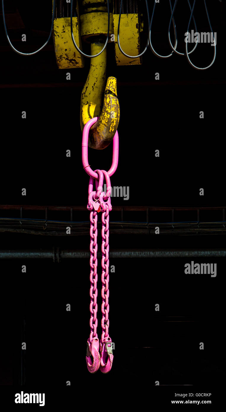 Gancio di una gru industriali, doppio gancio catena di colore rosa, appesa al gancio di giallo Foto Stock