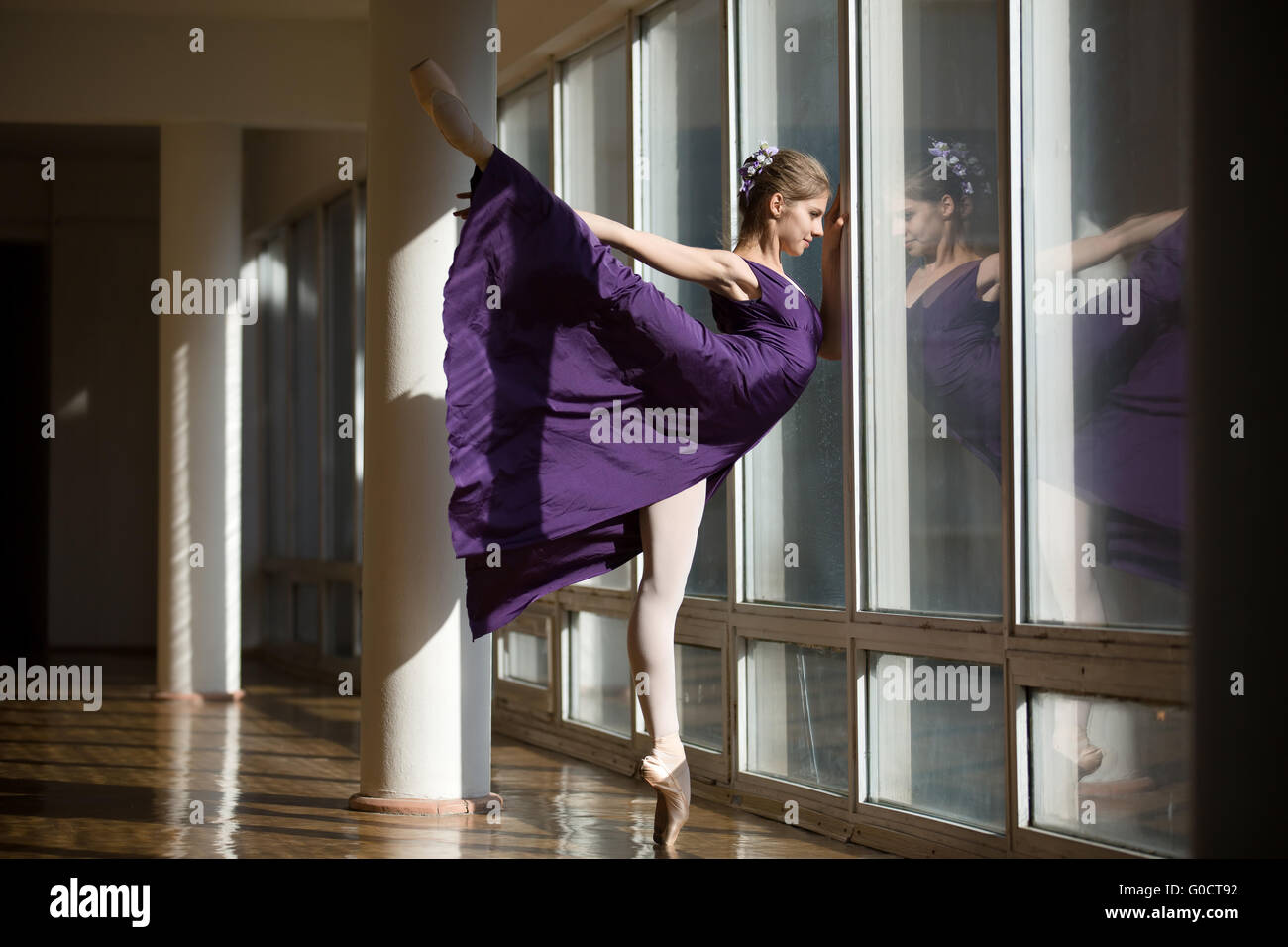 Graziosa ballerina dancing in un abito viola da gamba sollevato in alto, st Foto Stock