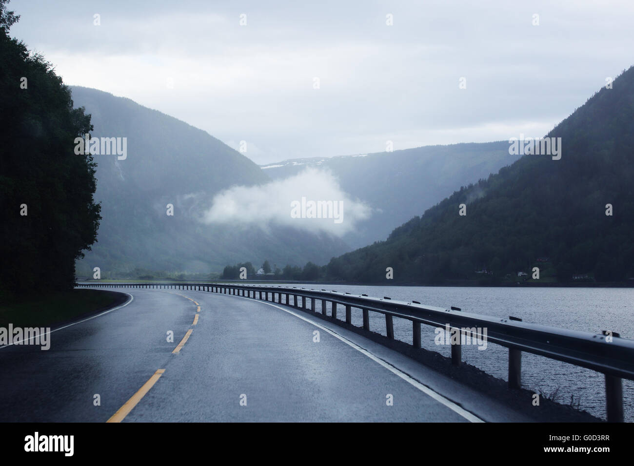 Vista sulla strada di montagna, le rocce e la foresta a brutta giornata estiva Foto Stock