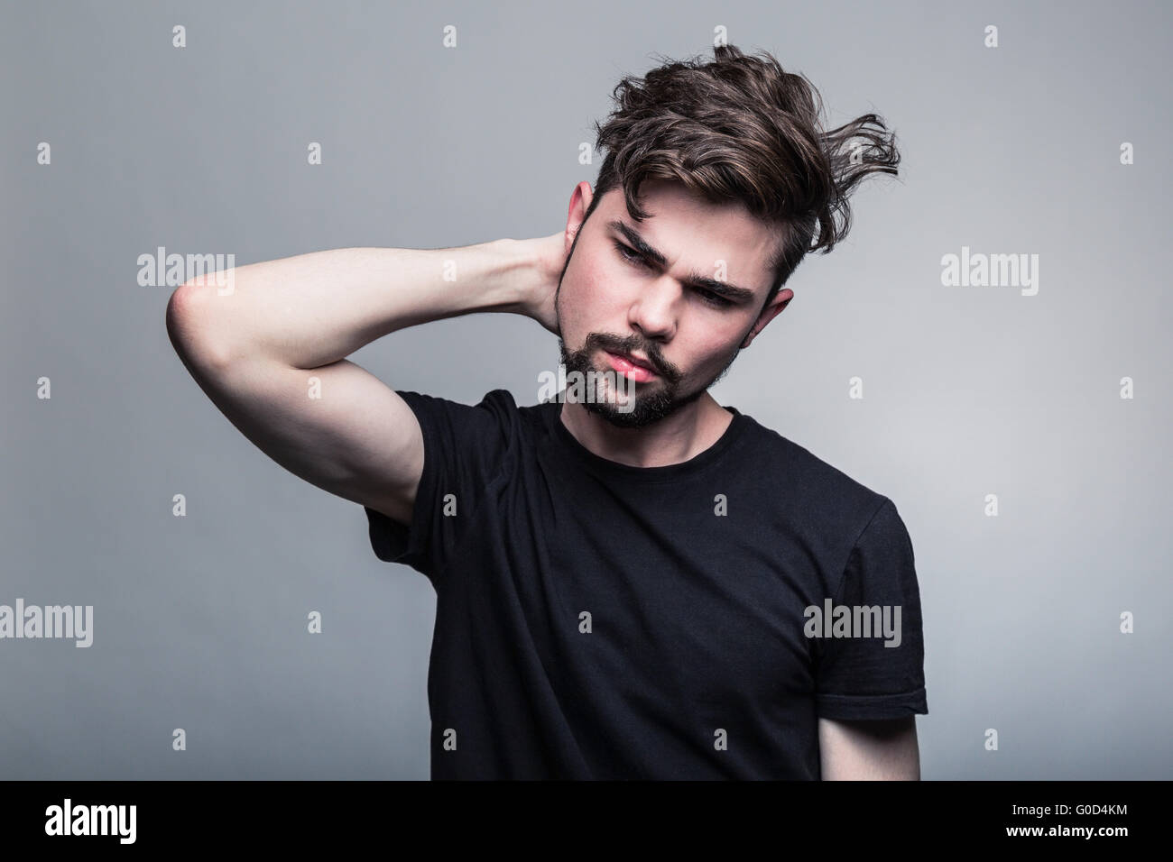 Giovane uomo bello dubitare su sfondo grigio Foto Stock