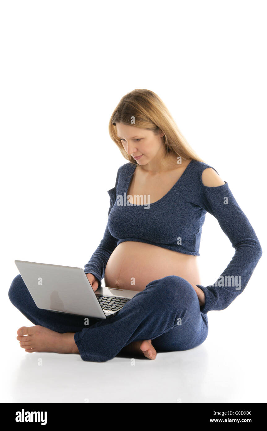 Donna incinta con un laptop seduto sul pavimento Foto Stock