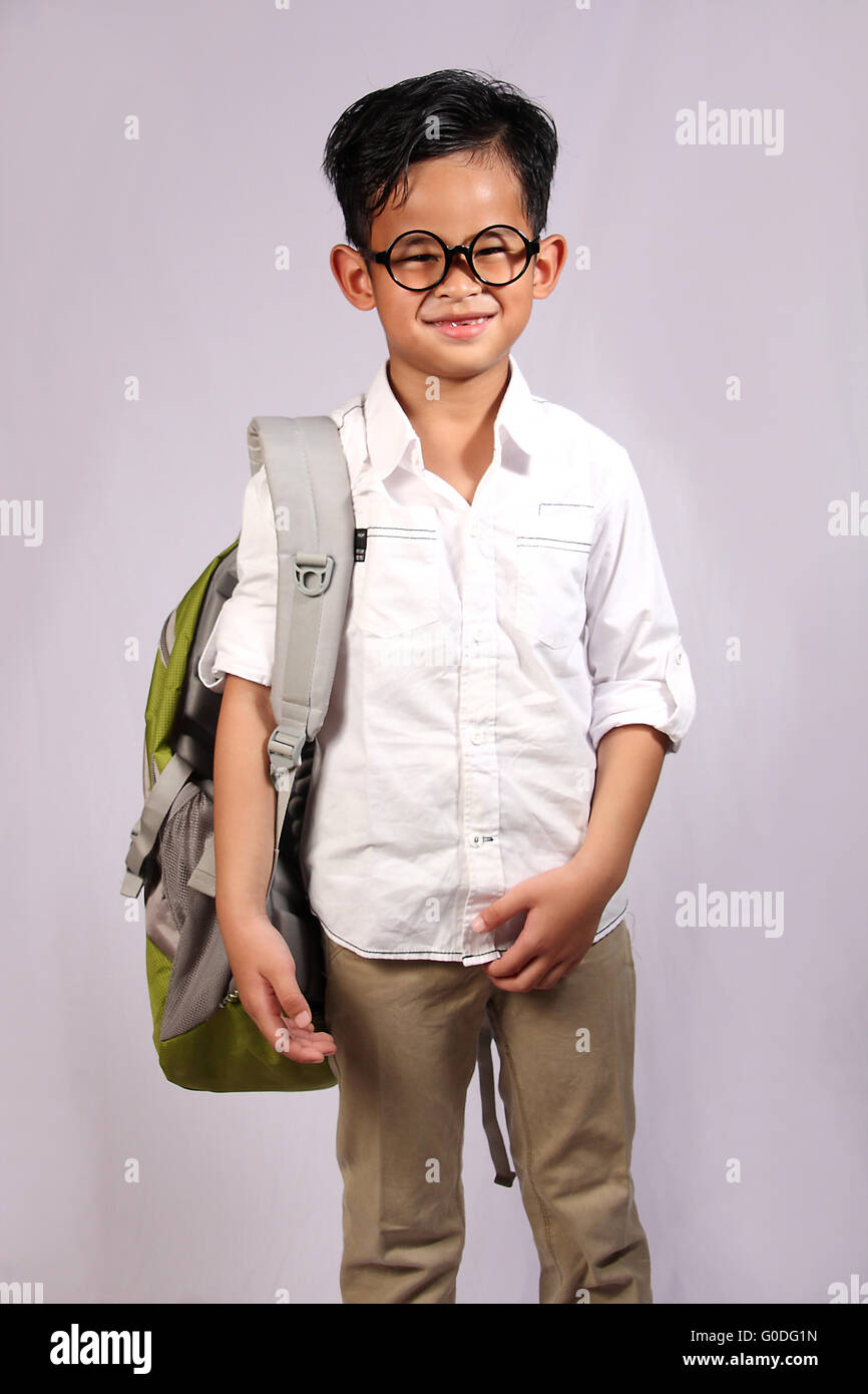 Felice e timido studente asiatico ragazzo indossa occhiali con una camicia bianca e zaino Foto Stock