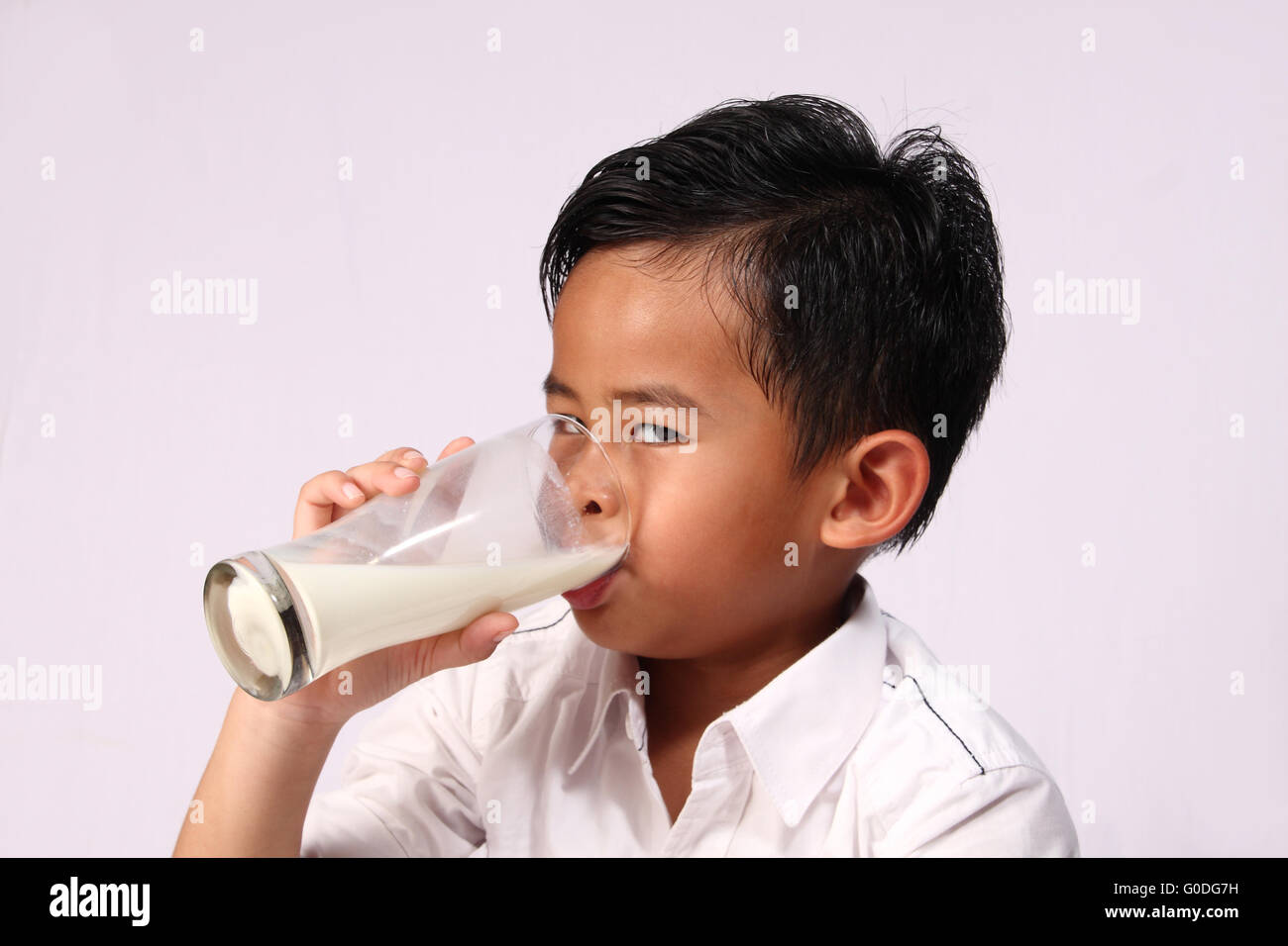 Felice e sorridente ragazzo asiatico bere un bicchiere di latte Foto Stock