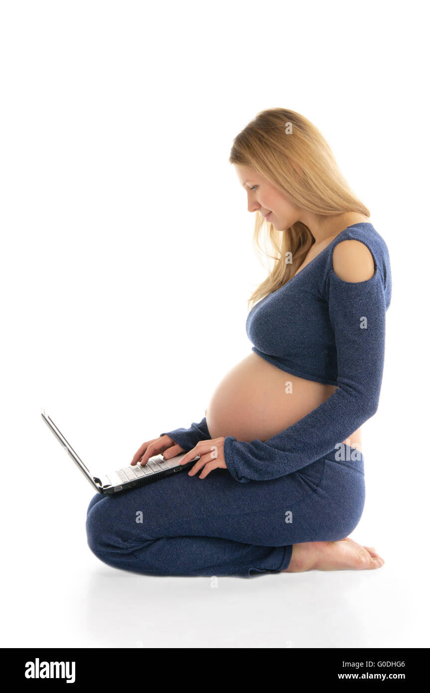 Donna incinta con un laptop seduto sul pavimento Foto Stock