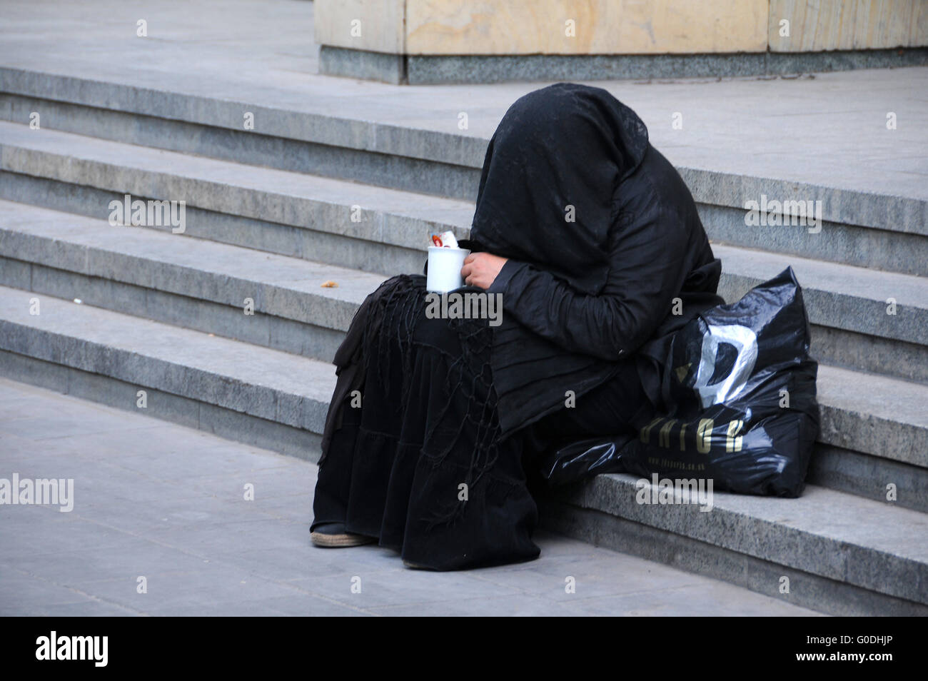 Beggar in abito nero Foto Stock