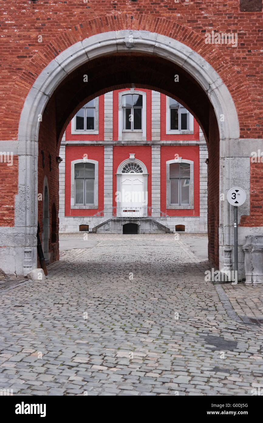 Strade in ciottoli e gate per l'edificio principale dell'abbazia di Stavelot visto attraverso un arco. Foto Stock