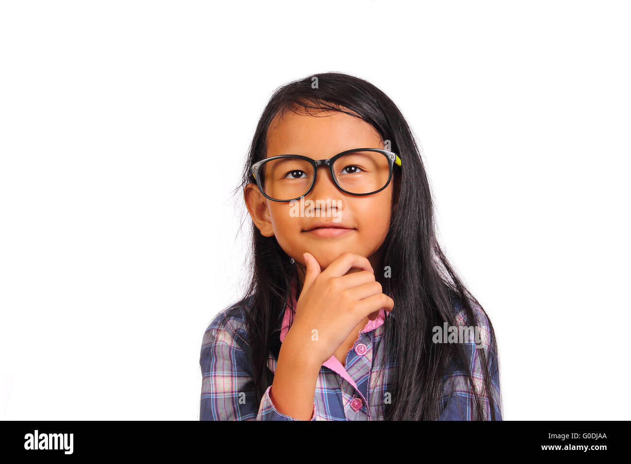 Bambina con gli occhiali di pensare e sorridente cercando fino alla parte superiore mentre si tocca il suo mento isolato su bianco Foto Stock