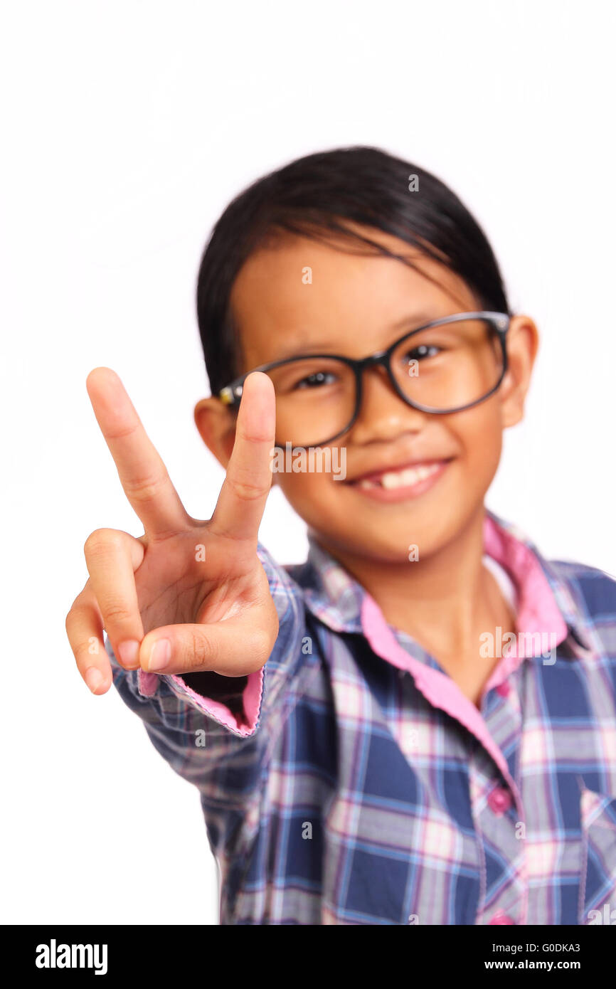 Carino bambina con gli occhiali che mostra due dita o gesto di pace di fronte a lei isolato su bianco Foto Stock