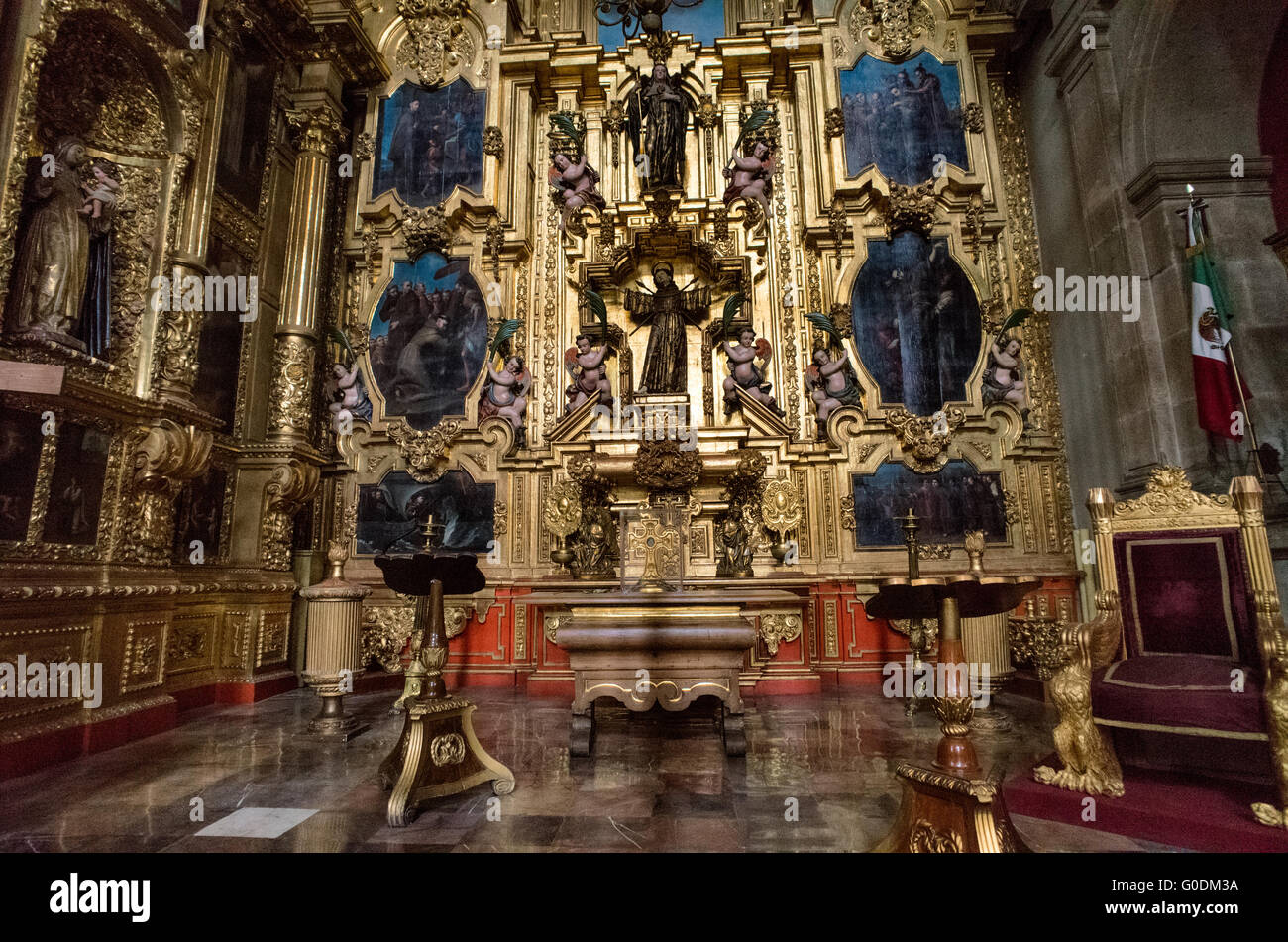 Cappella di San Francesco Retablo città del Messico // CITTÀ DEL MESSICO, MESSICO — la Cappella di San Francesco d'Assisi (Capilla de San Francisco de Asís) presenta un elaborato retablo dorato barocco con due importanti sculture in legno di San Francesco d'Assisi posizionate lungo l'asse verticale centrale. La cappella mostra il santo con stigmate visibili che indossano la tradizionale abitudine francescana, circondato da pannelli narrativi dipinti che raffigurano scene della sua vita, tra cui le stigmate, sermone agli uccelli ed esperienze mistiche. Costruito all'interno della Cattedrale metropolitana dell'assunzione del Most Foto Stock