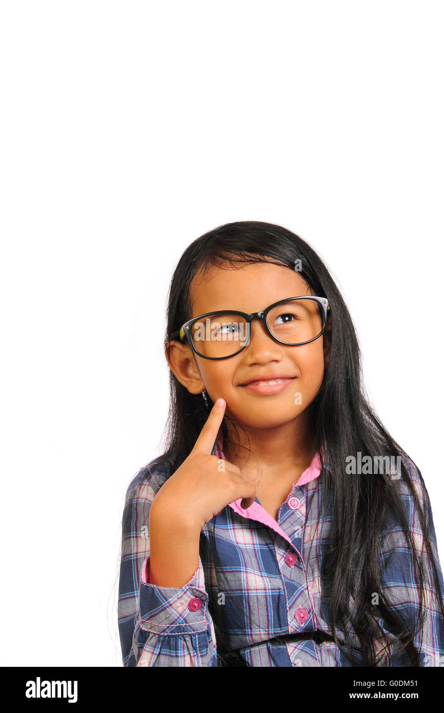 Bambina con gli occhiali di pensare e sorridente cercando fino alla parte superiore mentre si tocca la sua guancia isolato su bianco Foto Stock