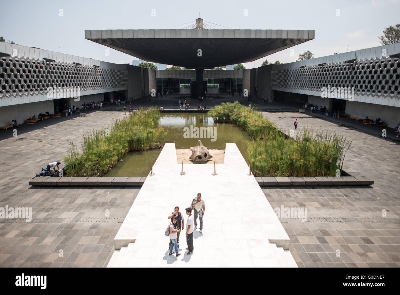 CITTÀ DEL MESSICO, Messico: L'iconica struttura a ombrello in cemento domina il cortile centrale del Museo Nazionale di Antropologia, progettato dall'architetto Pedro Ramírez Vázquez nel 1964. La suggestiva caratteristica architettonica, sostenuta da un unico pilastro, funge sia da punto focale scultoreo che da pratico rifugio. Il design innovativo esemplifica l'architettura modernista messicana della metà del secolo, fornendo al contempo un impressionante fulcro del principale museo archeologico del Messico. Foto Stock