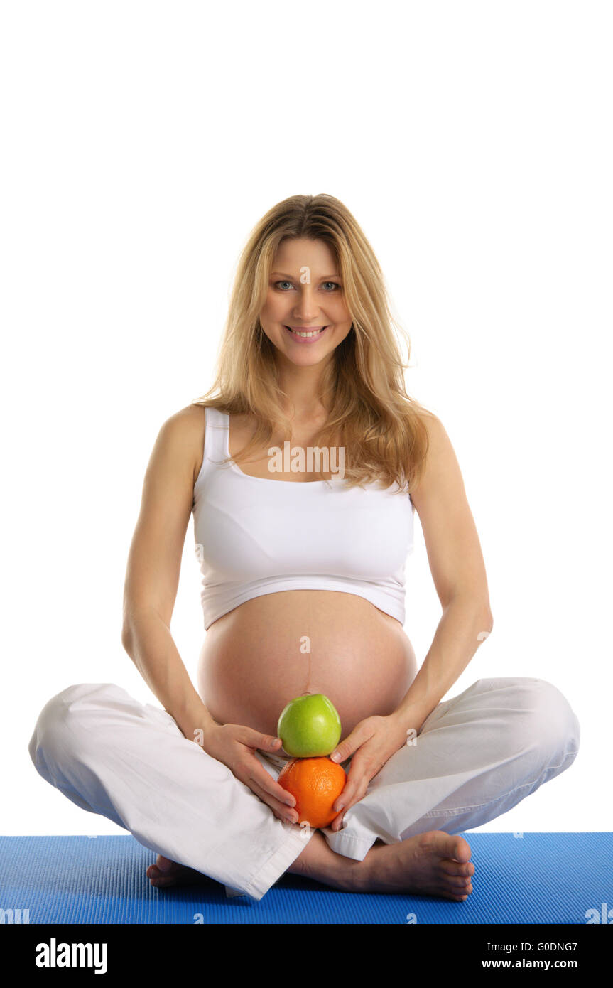 Donna incinta a praticare yoga e mantiene la frutta Foto Stock