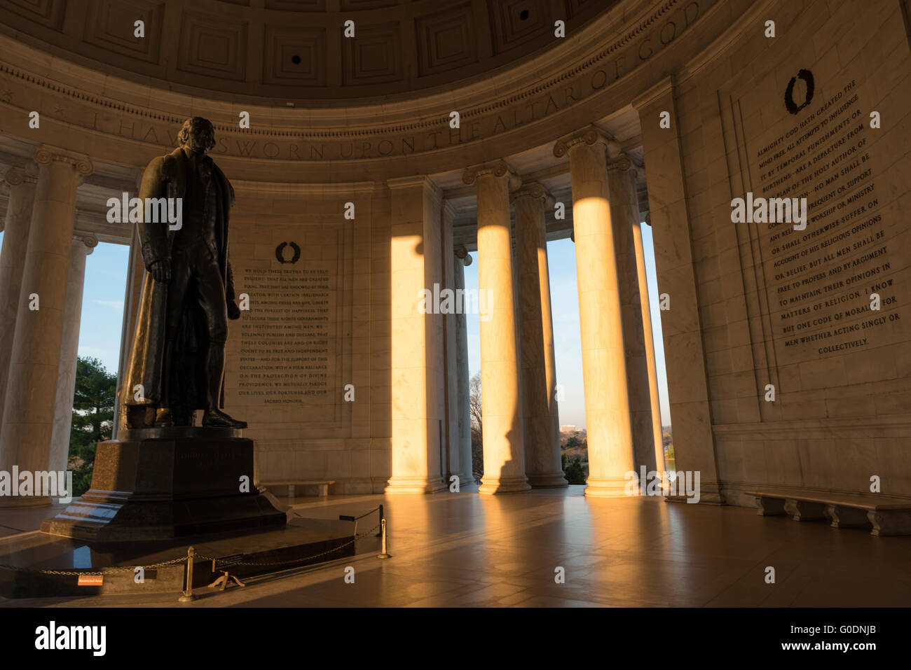 WASHINGTON DC - l'interno del Jefferson Memorial è illuminato dalla luce del mattino all'alba, gettando lunghe ombre dalle colonne di marmo. La statua di bronzo di 19 piedi di Thomas Jefferson, il terzo presidente degli Stati Uniti, si trova al centro del monumento neoclassico sul bacino di Tidal. Progettato dall'architetto John Russell Pope nello stile del Pantheon romano, il memoriale fu dedicato nel 1943. Foto Stock