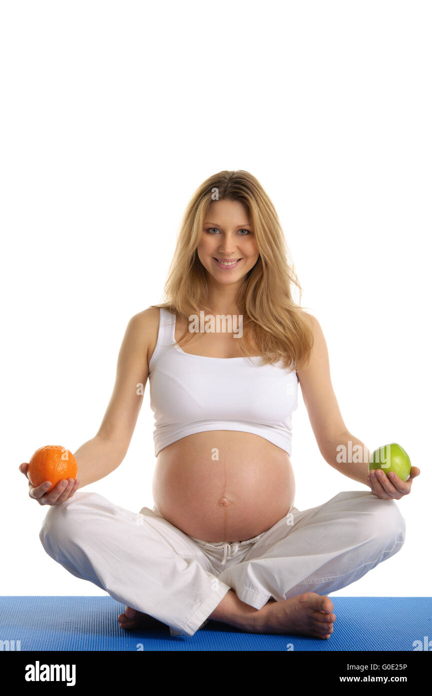 Donna incinta a praticare yoga e mantiene la frutta Foto Stock