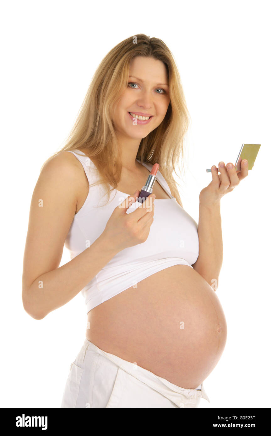 Sorridente donna incinta e specchio con il rossetto Foto Stock