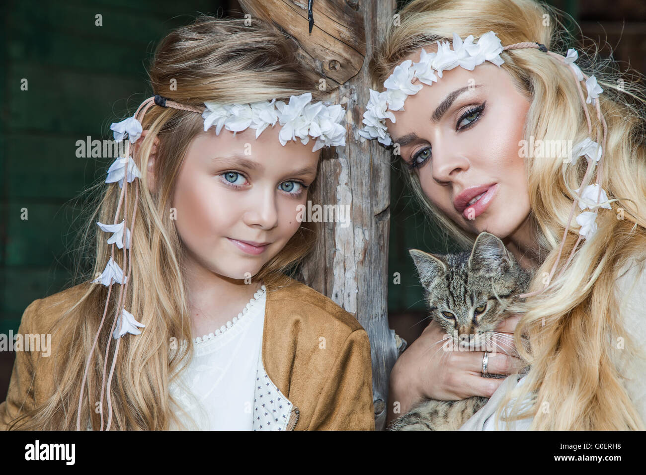 Una bella donna bionda con una bambina snuggling sul selvaggio west in costumi bianchi con un gatto sulle mani Foto Stock