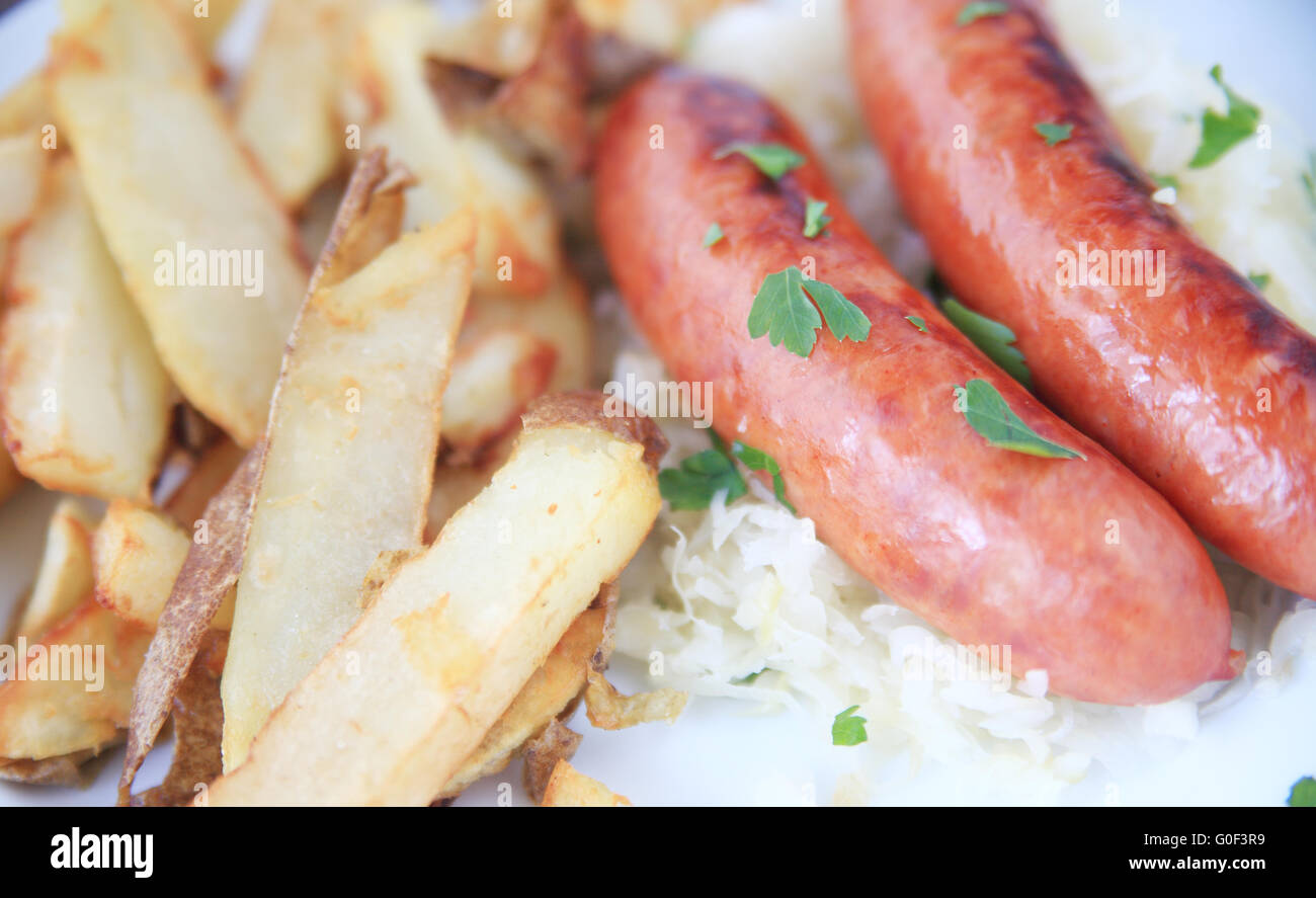 Salsicce con patate fritte e crauti cosparso con strappato foglie di coriandolo Foto Stock