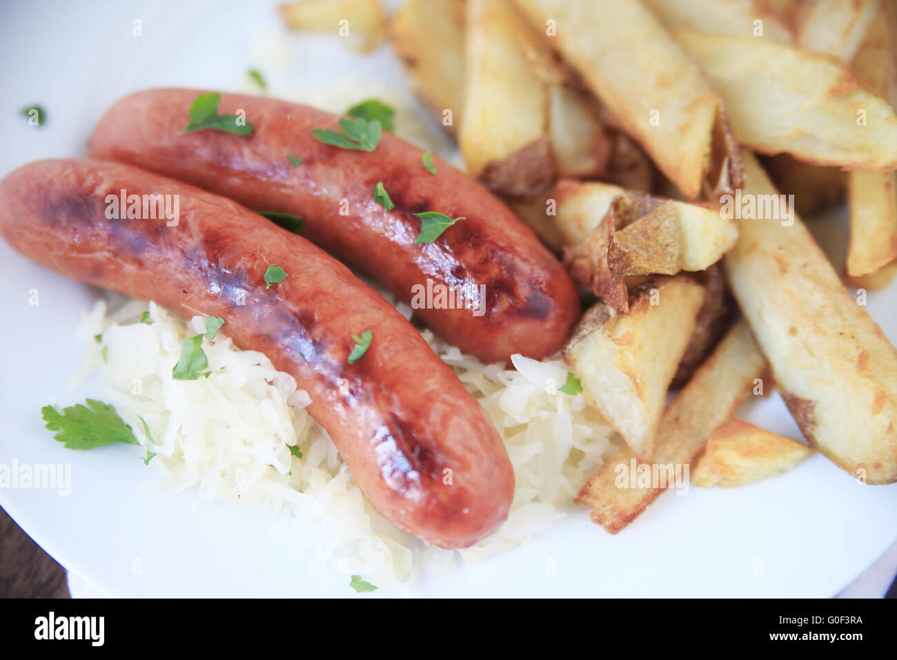 Due insaccati su crauti con un lato di patatine fritte Foto Stock