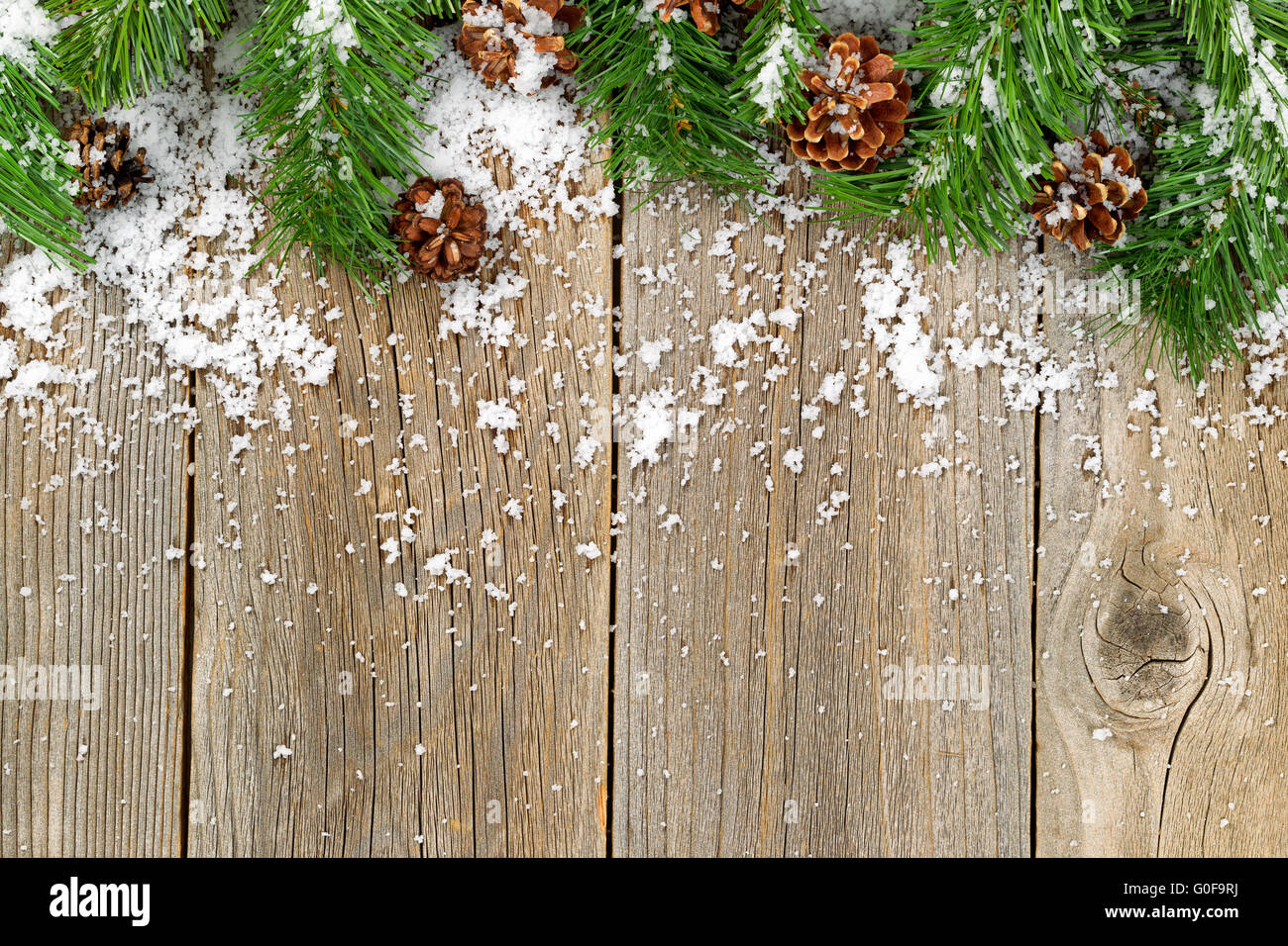 Bordo di Natale decorazioni con neve su rustiche tavole in legno Foto Stock