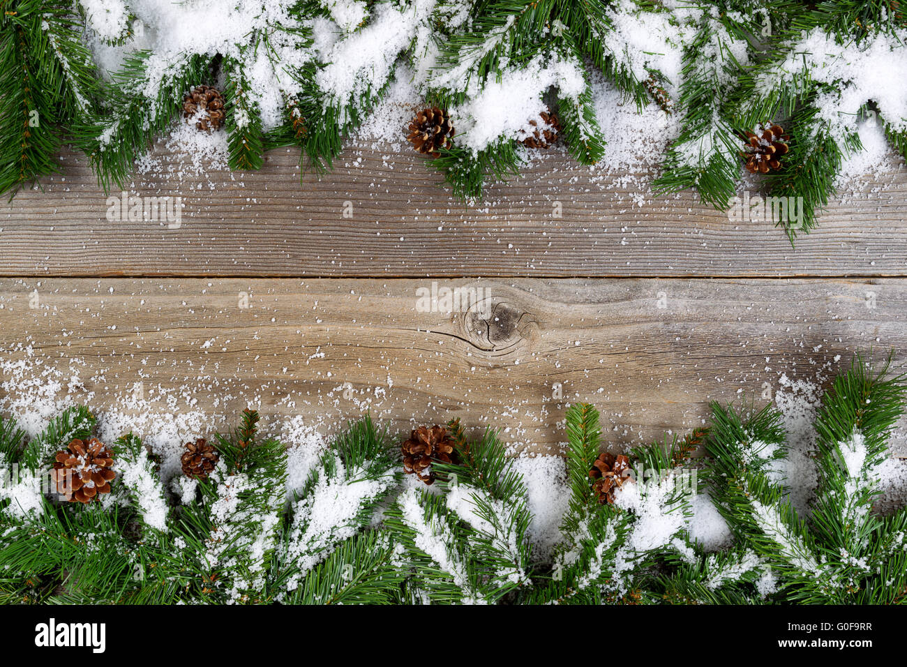 Bordo di Natale con coperta di neve rami su rustiche tavole in legno Foto Stock