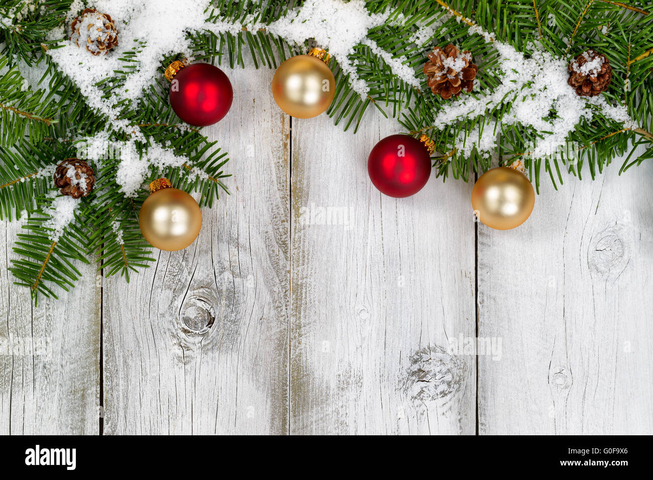 Coperte di neve rami di abete e di ornamenti sul bianco rustico di tavole di legno Foto Stock