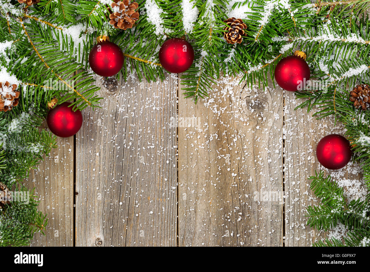 Coperte di neve rami di abete rosso con ornamenti e rocche su rustiche tavole in legno Foto Stock