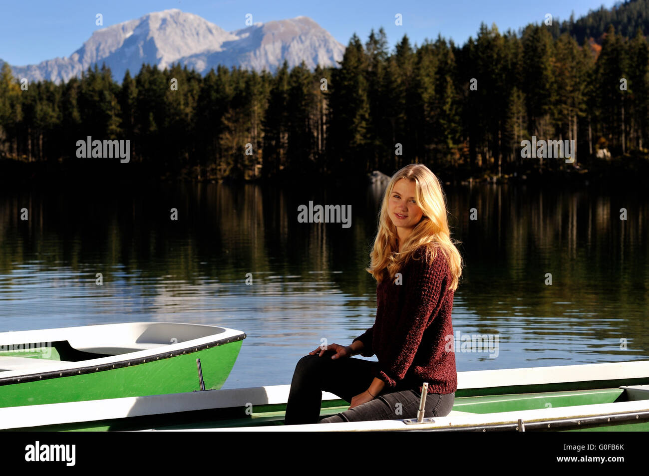 Giovane donna seduta in una barca, Hintersee, Bavaria Foto Stock