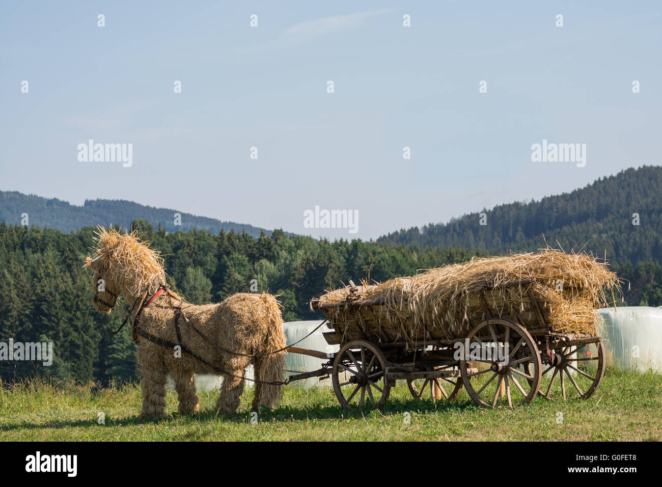 Cavallo di paglia gonfiato con paglia carro in legno in aperta campagna Foto Stock
