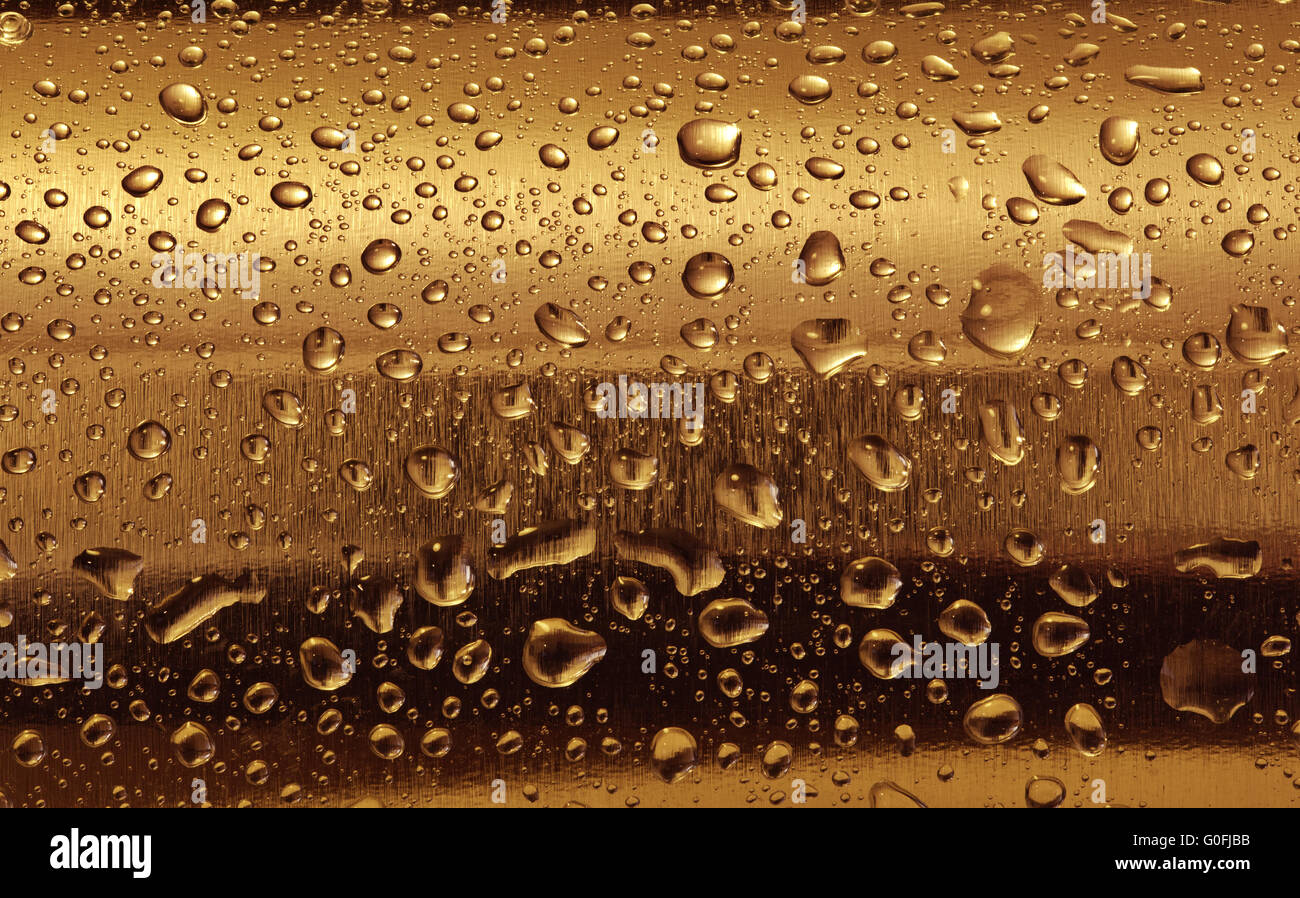Piastra di oro con gocce d'acqua sulla superficie arrotondata. Sfondo Foto Stock