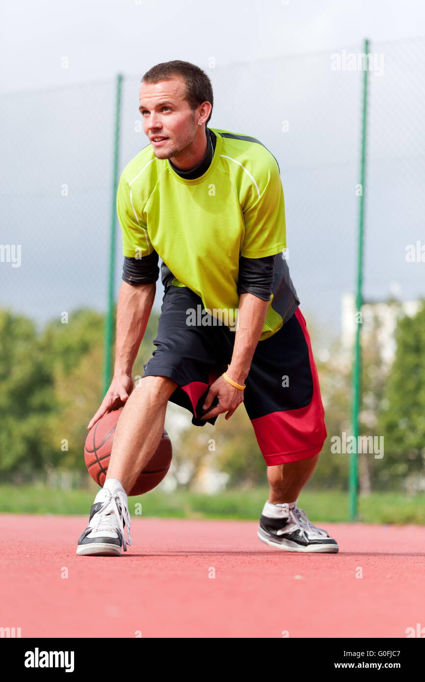 Giovane uomo su campo da pallacanestro dribbling con sfera. Streetball Foto Stock