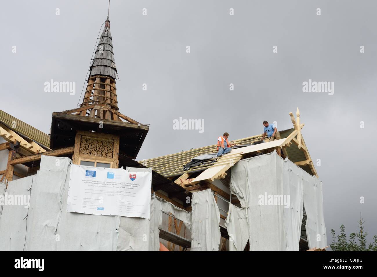 Gli uomini di ripristino del tetto della chiesa come parte del divertimento europeo Foto Stock