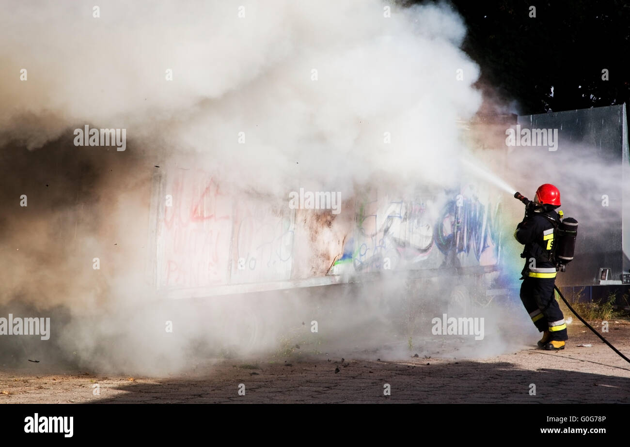 I vigili del fuoco nella lotta contro un incendio di un luogo di rifiuti. Nuvola di fumo che circonda Foto Stock