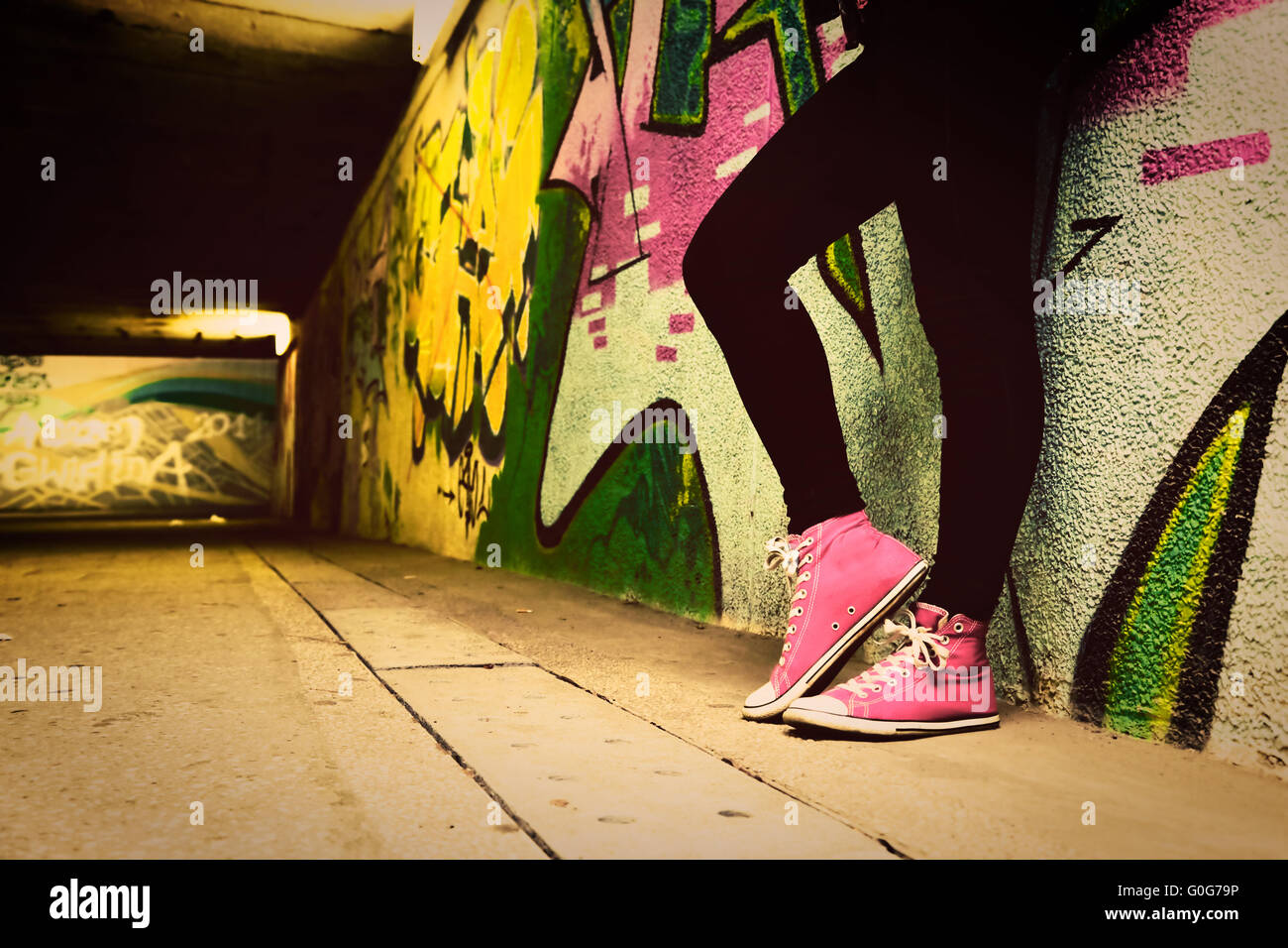 Close up di rosa sneakers indossata da un adolescente. Grunge muro di graffiti Foto Stock