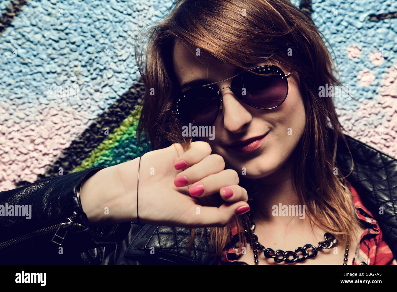 Elegante ragazza alla moda in posa contro il coloratissimo graffito parete. La moda Foto Stock