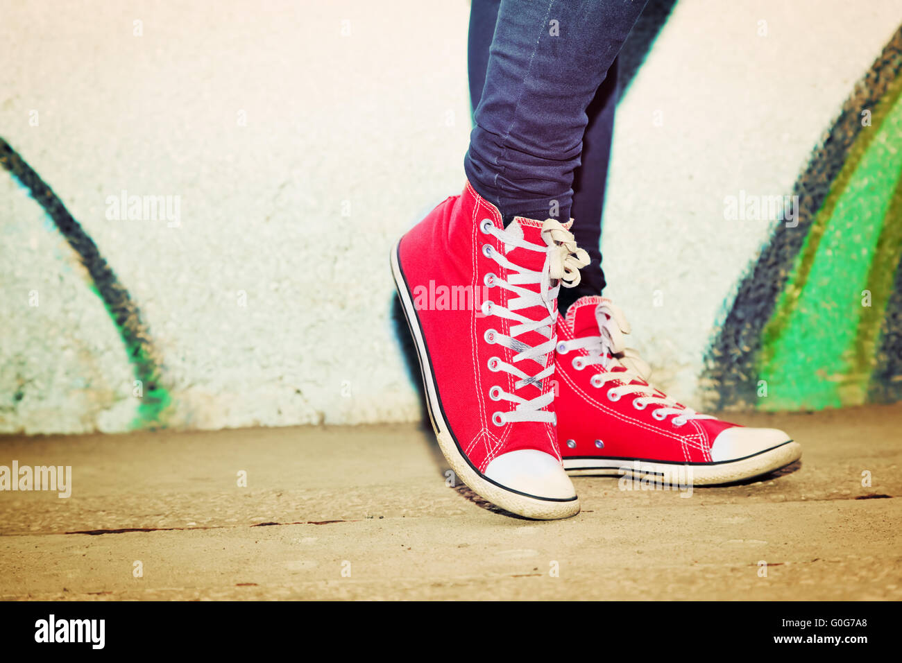 Close up red sneakers indossata da un adolescente. Grunge muro di graffiti Foto Stock