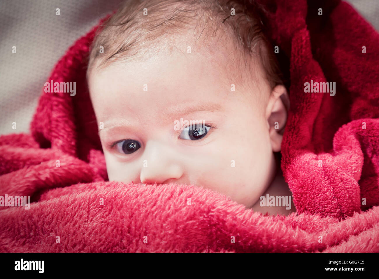 Bella 3 mesi bambino giacente sul letto coperto con red coperta. Ritratto morbido Foto Stock