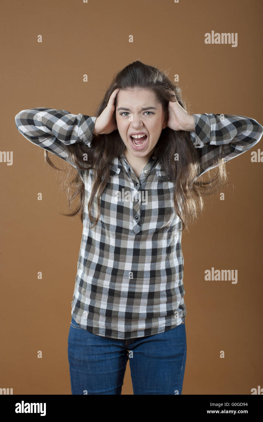 Una giovane ragazza tiene le mani dietro la sua testa e urla. Foto Stock