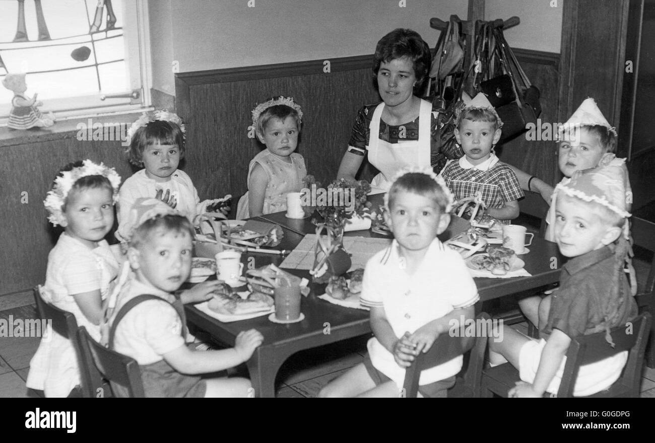 Anni sessanta, istruzione, educazione prescolare, kindergarten, i ragazzi e le ragazze da 3 a 5 anni e la kindergartener 25-30 anni seduti ad un tavolo, Frank Foto Stock