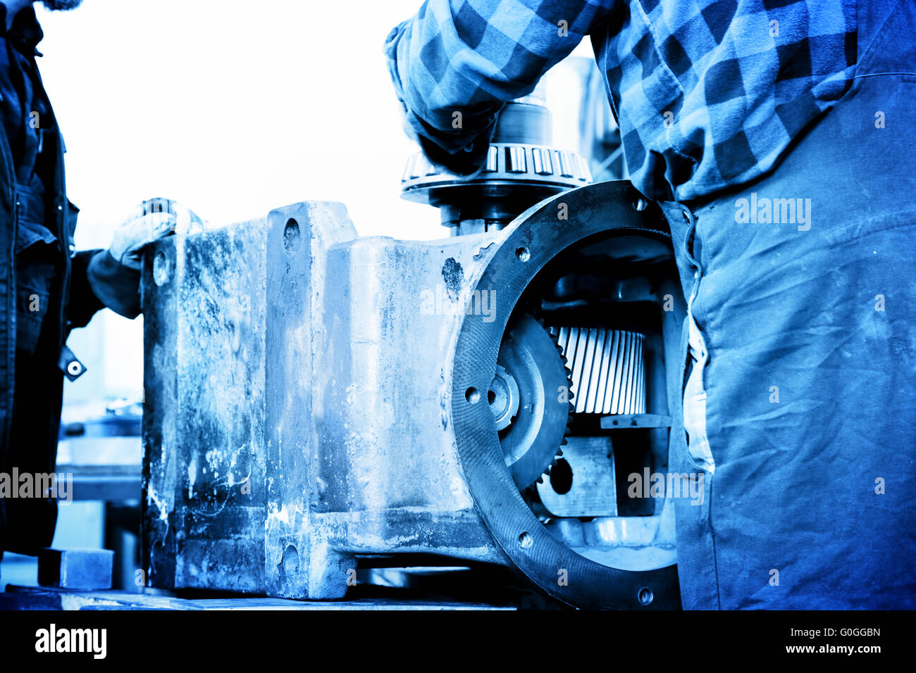 Riparazione dei lavoratori, opera sul vecchio elemento di ingranaggio in officina. L'industria Foto Stock