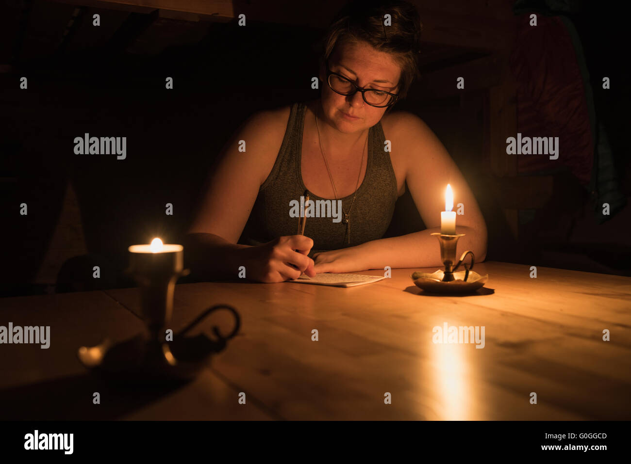 Escursionista femmina scrive nel journal a lume di candela al rifugio Abiskojaure, Kungsleden trail, Lapponia, Svezia Foto Stock