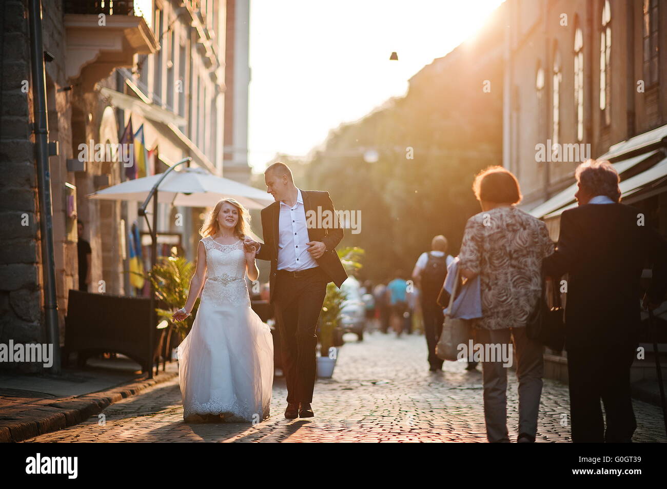Coppie in viaggio di nozze a piedi sul tramonto strade della città Foto Stock