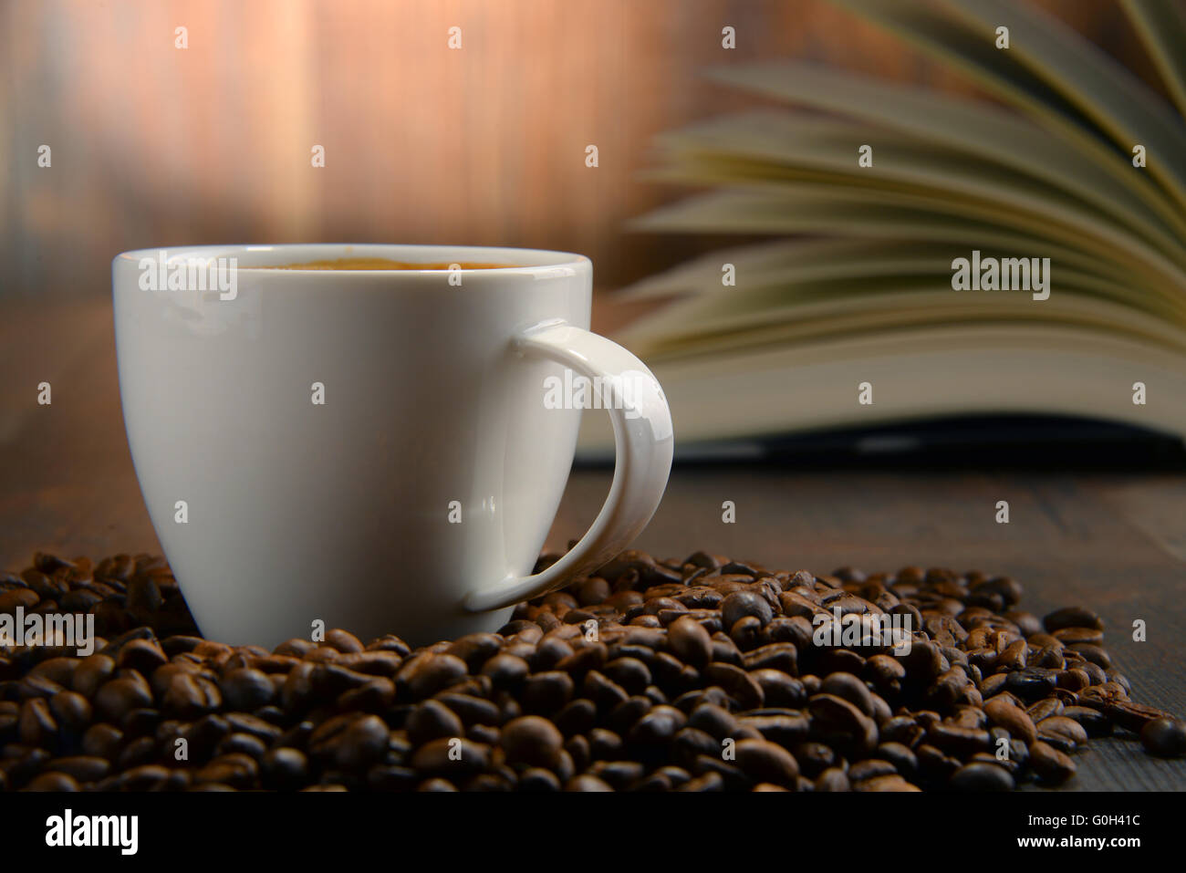 Composizione con il bianco tazza di caffè e libro aperto. Foto Stock