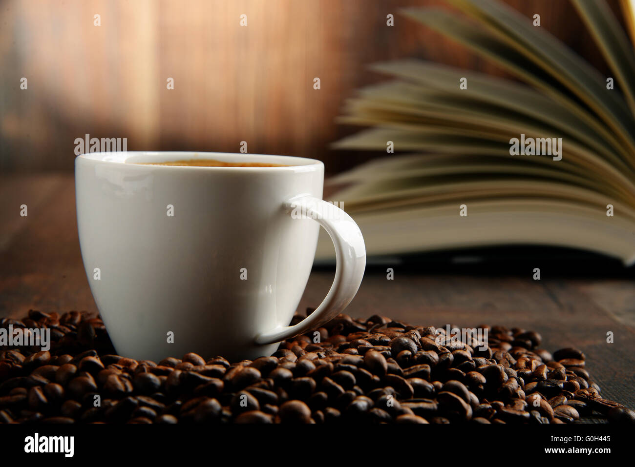 Composizione con il bianco tazza di caffè e libro aperto. Foto Stock