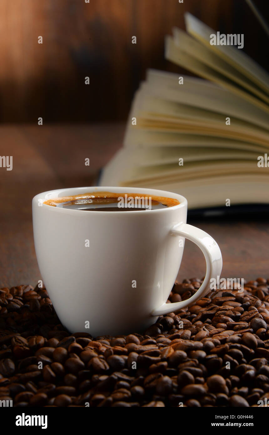 Composizione con il bianco tazza di caffè e libro aperto. Foto Stock
