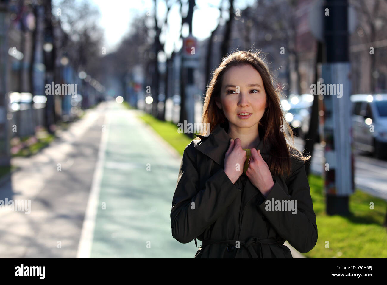 Bella donna asiatica con un cappotto di oliva sulla strada Foto Stock