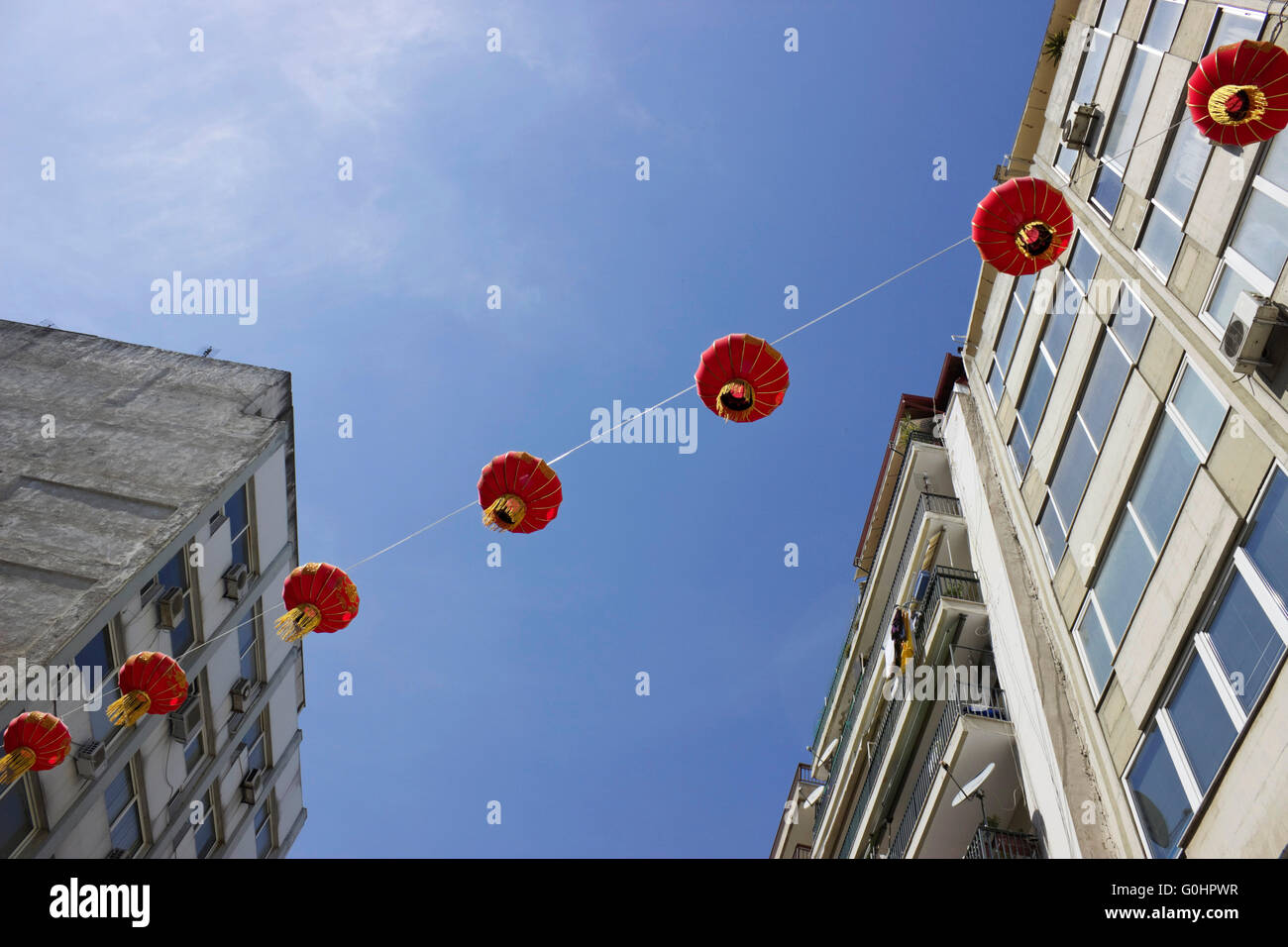 Fila di top illuminato rosso Cinese lanterne di overhead di ornamenti e gli edifici in background. Chinatown, Salonicco, Grecia Foto Stock