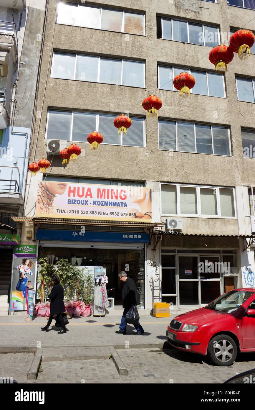 Fila di rosso Cinese lanterne di overhead appeso su una stringa e il commercio business store in Chinatown's market place. Salonicco Foto Stock