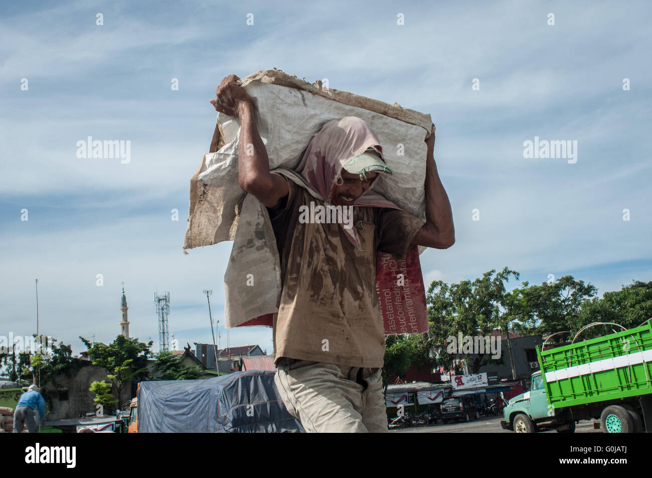 Un uomo porta un sacco di cemento a Paotere Porto di Makassar, Indonesia. Foto Stock