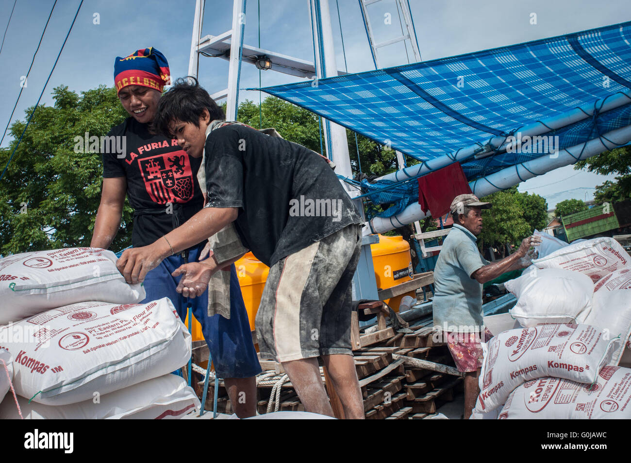 Lavoratori caricare sacchi di grano in una barca a Paotere Porto di Makassar, Indonesia. Foto Stock